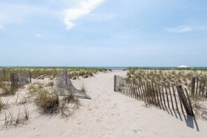 A sandy beach path with wooden fences and sparse vegetation. - Hobbs Realty - "Waves of Grace": Elegant Oceanfront Home with Stunning Views and Private Pool (Holden Beach)