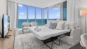 A modern hotel room with a large bed, a TV, a view of the ocean, and a balcony. - Hilton 2BR Retreat Sky High Ocean Views Pool (Surfers Paradise)
