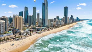 A coastal cityscape with high-rise buildings, a sandy beach, and the ocean. - Hilton 2BR Retreat Sky High Ocean Views Pool (Surfers Paradise)