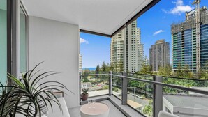 A balcony with a round table, seating, and a potted plant. - Broadbeach Elite Luxury Residence | 5‑Star Resort (Broadbeach)