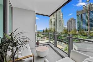 Ein Balkon mit rundem Tisch, Sitzgelegenheiten und einem Blumentopf.