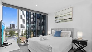 A modern hotel room with a large bed, a desk, and a view of the cityscape. - Broadbeach Elite Luxury Residence | 5‑Star Resort (Broadbeach)