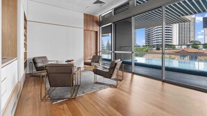 A modern hotel room with a large sliding glass door to a balcony, a wooden floor, and a seating area with a table and chairs. - Broadbeach Elite Luxury Residence | 5‑Star Resort (Broadbeach)