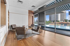 Ein modernes Hotelzimmer mit einer großen Schiebeglasdoor zum Balkon, Holzboden und einer Sitzecke mit Tisch und Stühlen.