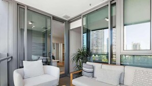 A modern living room with a sofa, a coffee table, and a large window with a view of buildings. - Broadbeach Elite Luxury Residence | 5‑Star Resort (Broadbeach)