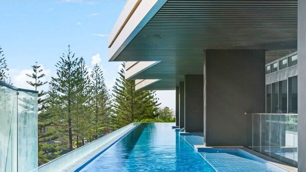 A modern building with a long, narrow pool extending from the entrance. - Broadbeach Elite Luxury Residence | 5‑Star Resort (Broadbeach)