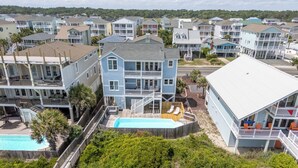 Una propiedad frente a la playa con piscina, varios balcones y vistas a casas vecinas.