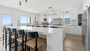 Una cucina moderna con una grande isola, sgabelli da bar e vista sull'oceano.