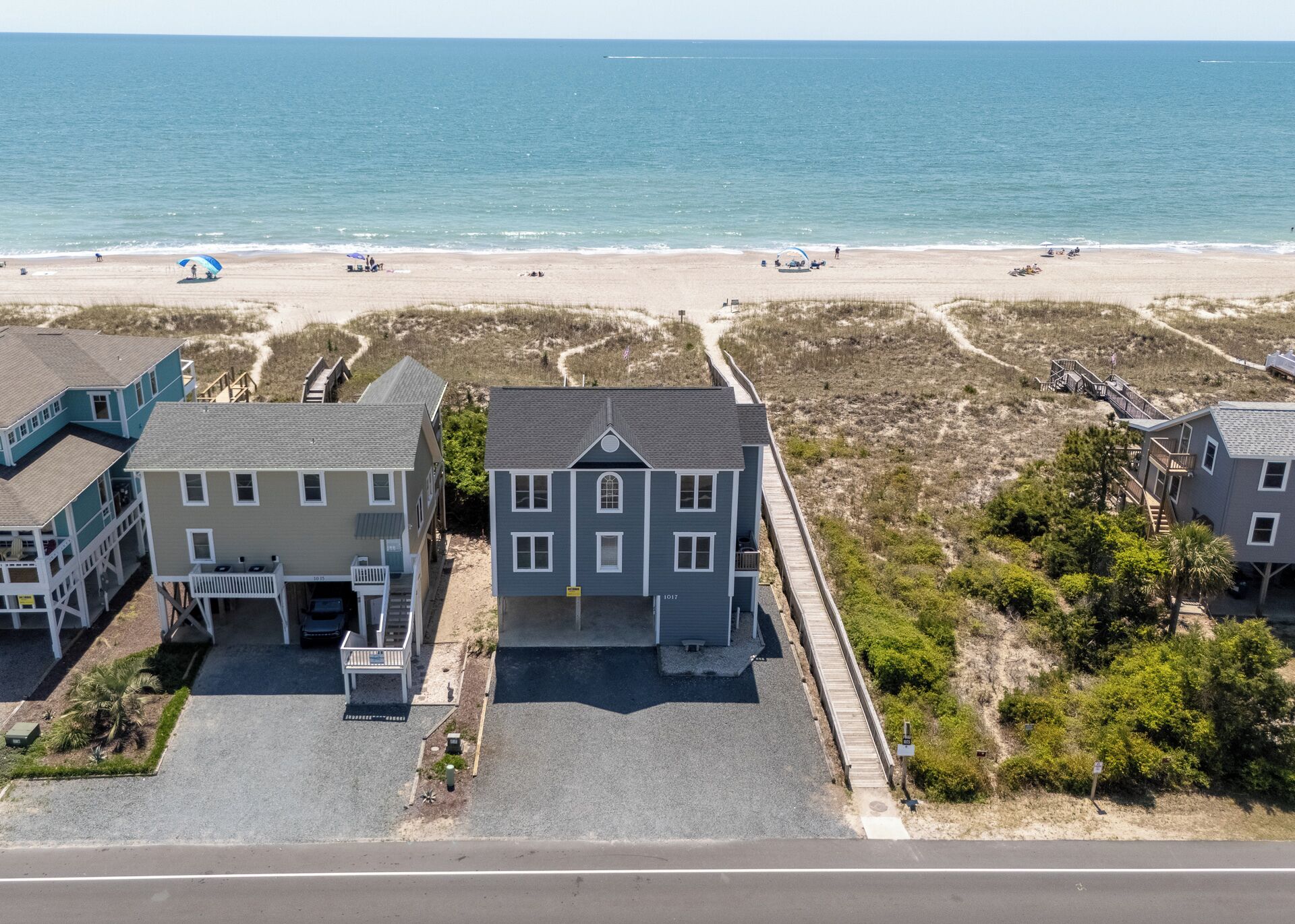 Una propiedad frente a la playa con una casa grande, un patio cubierto y vistas al mar.