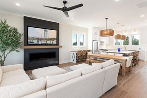 A modern living room with a fireplace, a large TV, and a sofa. - Sunset Skies: Stylish 4BR beach home in Holden Beach with a private pool. (Holden Beach)