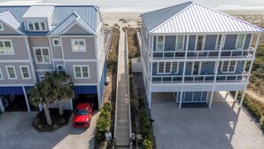 Un edificio a due piani con un balcone al secondo piano, un vialetto e un'auto rossa parcheggiata nel garage.