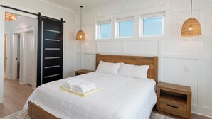 Una camera da letto con un letto, un comodino in legno, una porta scorrevole nera e una finestra vista.