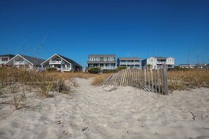 A beachfront property with multiple houses, a sandy beach, and a wooden fence. - Oceanfront duplex in Holden Beach, 4 bedrooms, stunning views, sleeps 10. (Holden Beach)