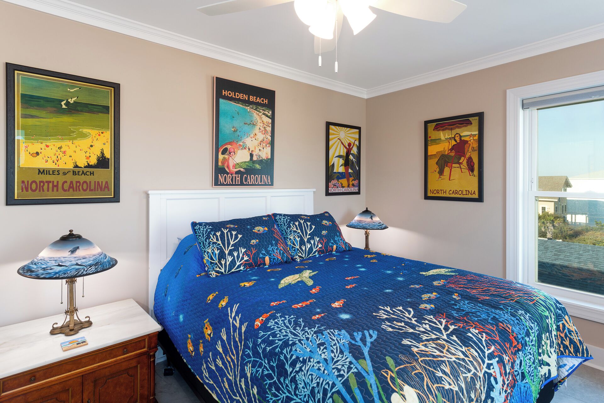 Ein Schlafzimmer mit einem Bett, einem Nachttisch, einer Lampe und Wandbildern mit Motiven von North Carolina.
