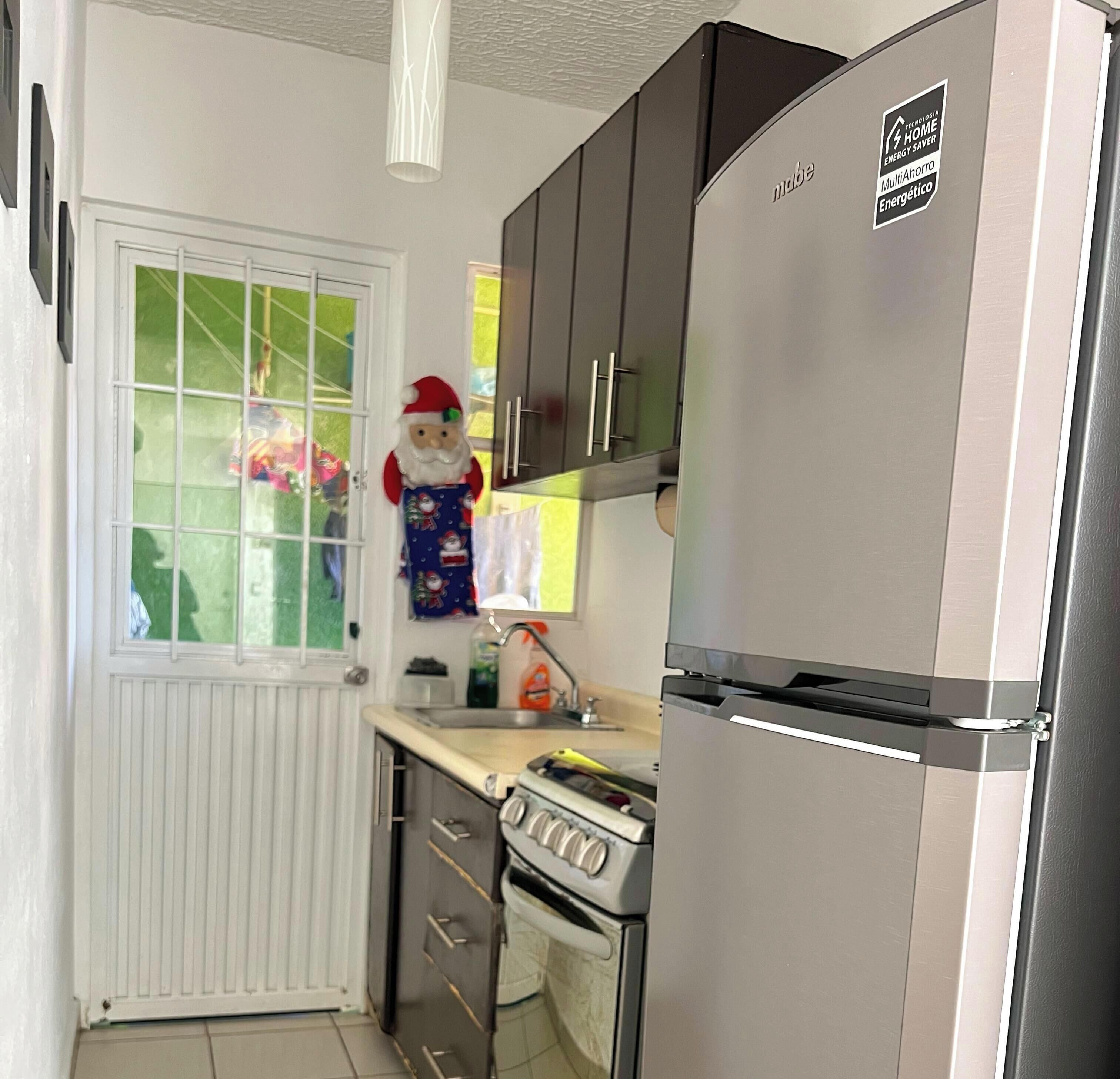 A compact kitchen with a built-in stove, a refrigerator, and a window with a view of the outside.