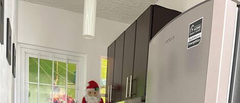 A compact kitchen with a built-in stove, a refrigerator, and a window with a view of the outside.