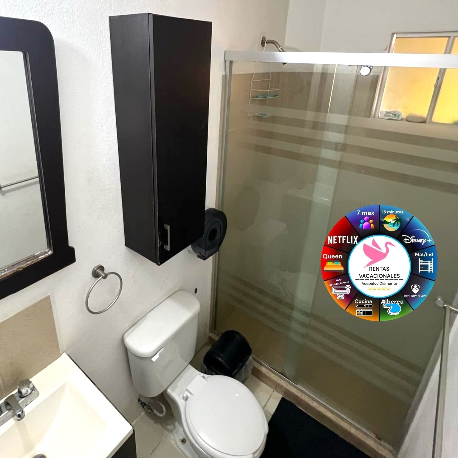 Een badkamer met toilet, wastafel en een douchecabine van glas.