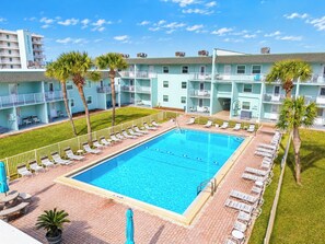 Ein Hotel mit Schwimmbad, mehreren Balkonen und Palmen.