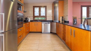 Cozinha moderna com armários de madeira, eletrodomésticos de aço inoxidável e uma máquina de lavar louça.
