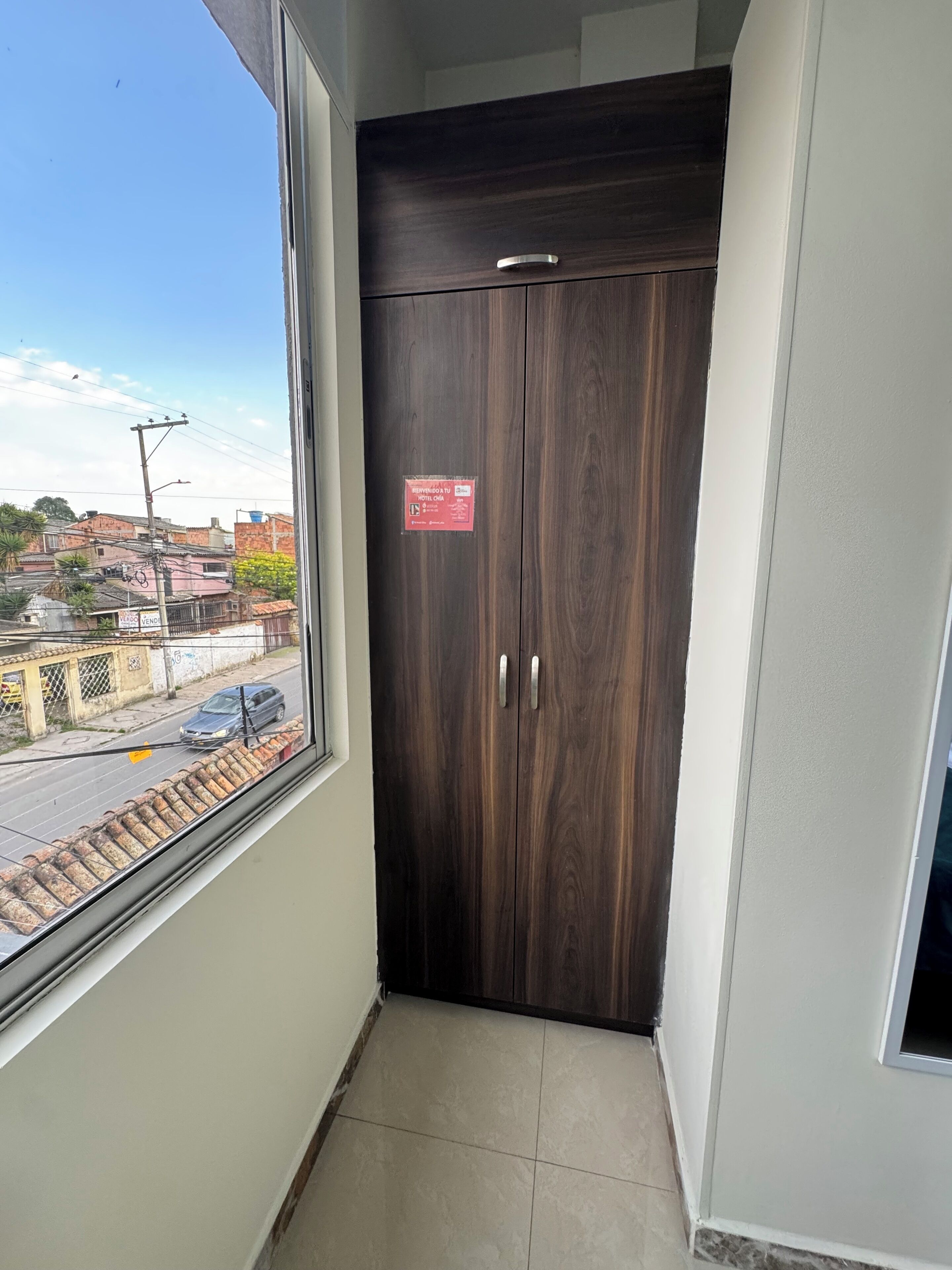 Une armoire en bois sombre, dotée d’une poignée, d’une fenêtre et d’une enseigne rouge accrochée au mur.