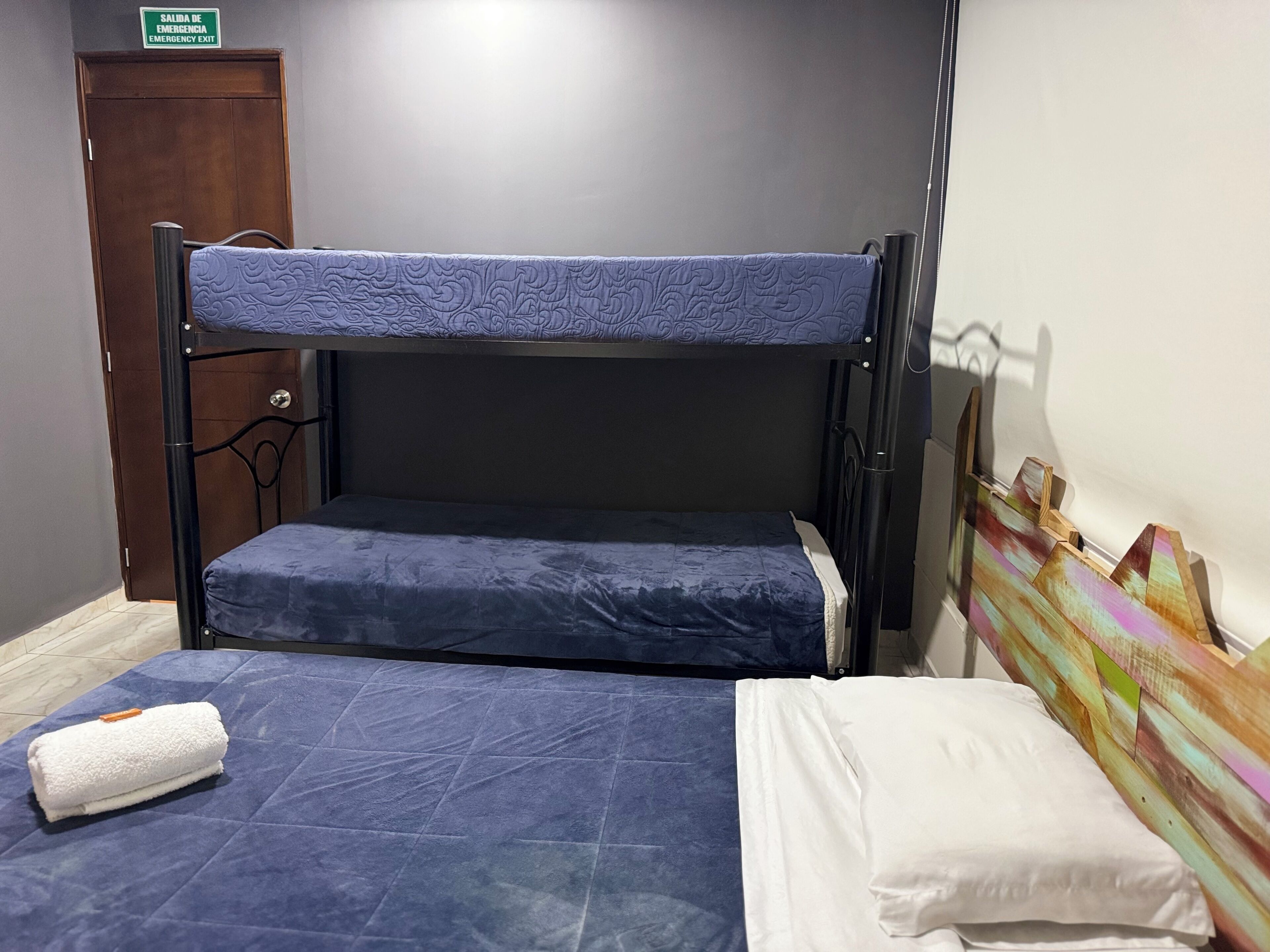 Una cama litera con un colchón azul, una almohada blanca y una toalla blanca enrollada en la litera inferior.