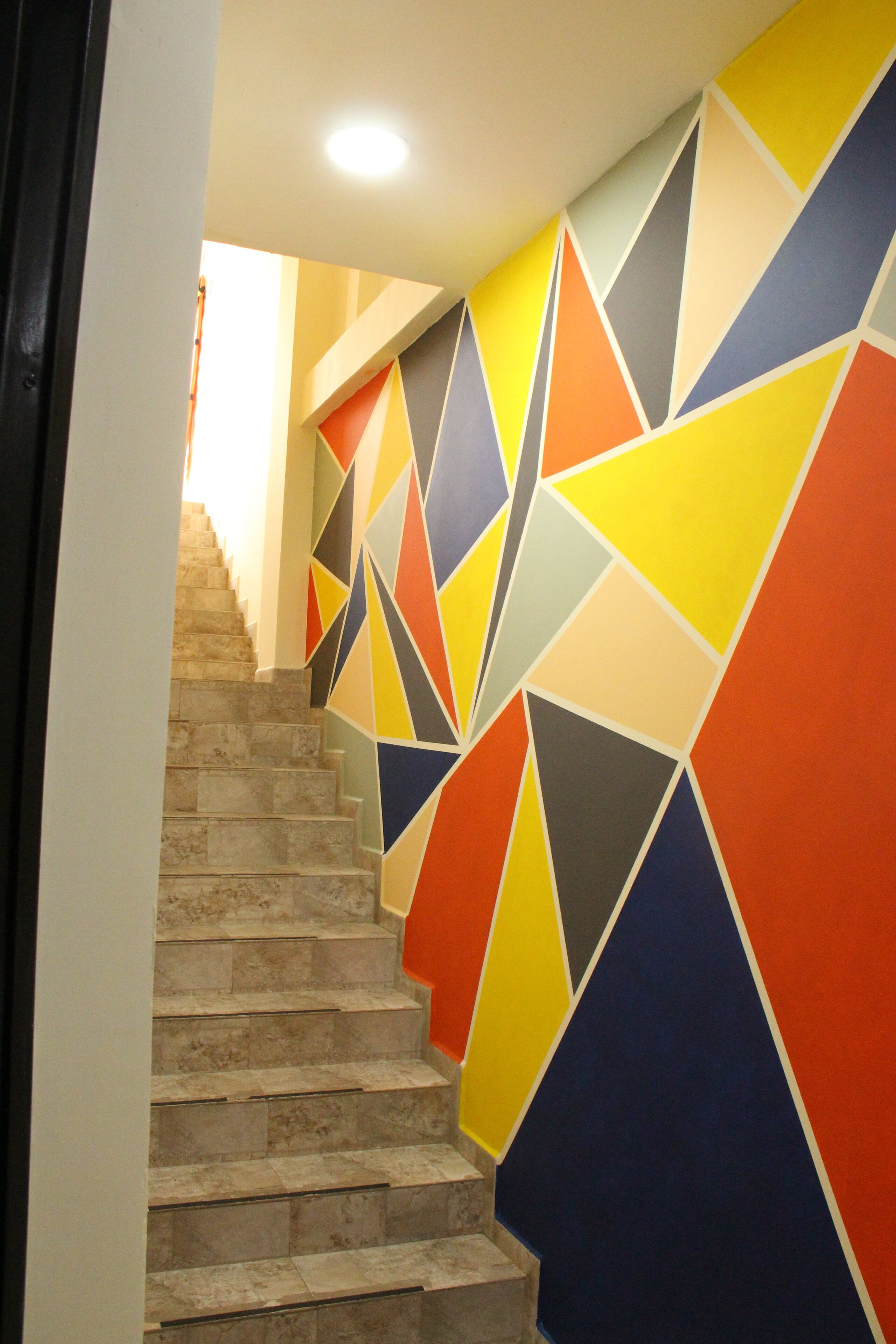 Eine Treppe mit einer Wand mit geometrischem Muster und einer schlichten Wand auf der anderen Seite.