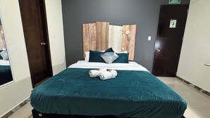 A hotel room with a bed, a headboard, a door, and a sign indicating an emergency exit. - Tu Hotel Chía (Chía)