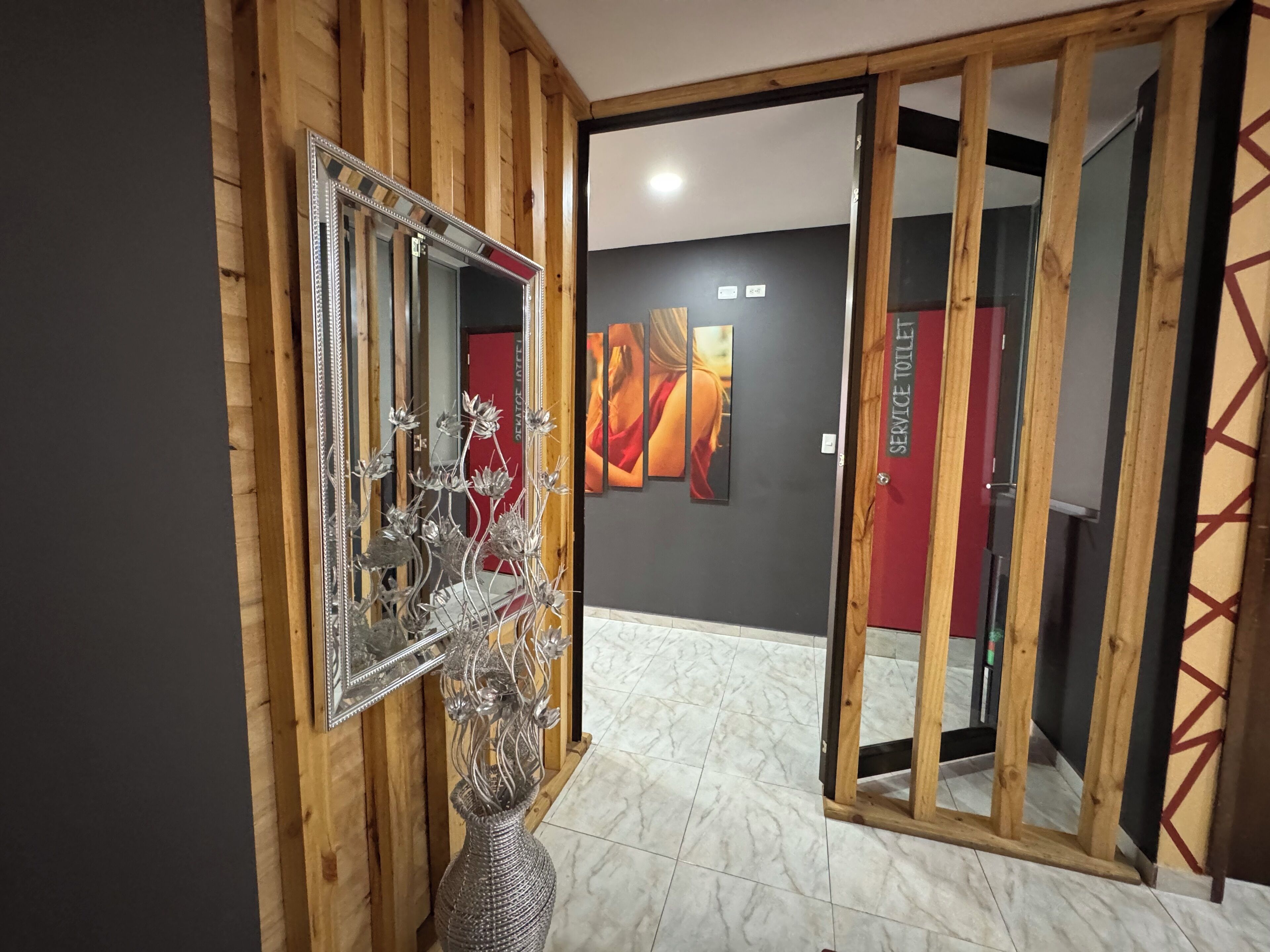 Una habitación con paneles de madera, un espejo, un jarrón decorativo y piso de baldosas.