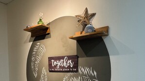 A wall with a circular design, two wooden shelves with decorative items, and a sign with the text 'together is my favorite place to be'. - Tu Hotel Chía (Chía)