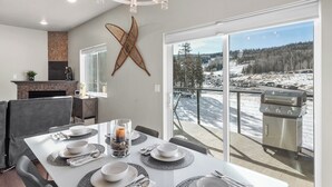 Ein Essbereich mit einem Tisch für sechs Personen, einem Kamin und einem großen Fenster mit Blick auf eine verschneite Landschaft.
