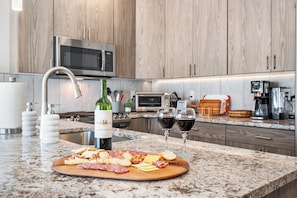 A modern kitchen with a marble countertop, a wine bottle, and a charcuterie board. - Brian Head Retreat - Walk to Lifts/Family Friendly/Spacious/Modern (Brian Head)
