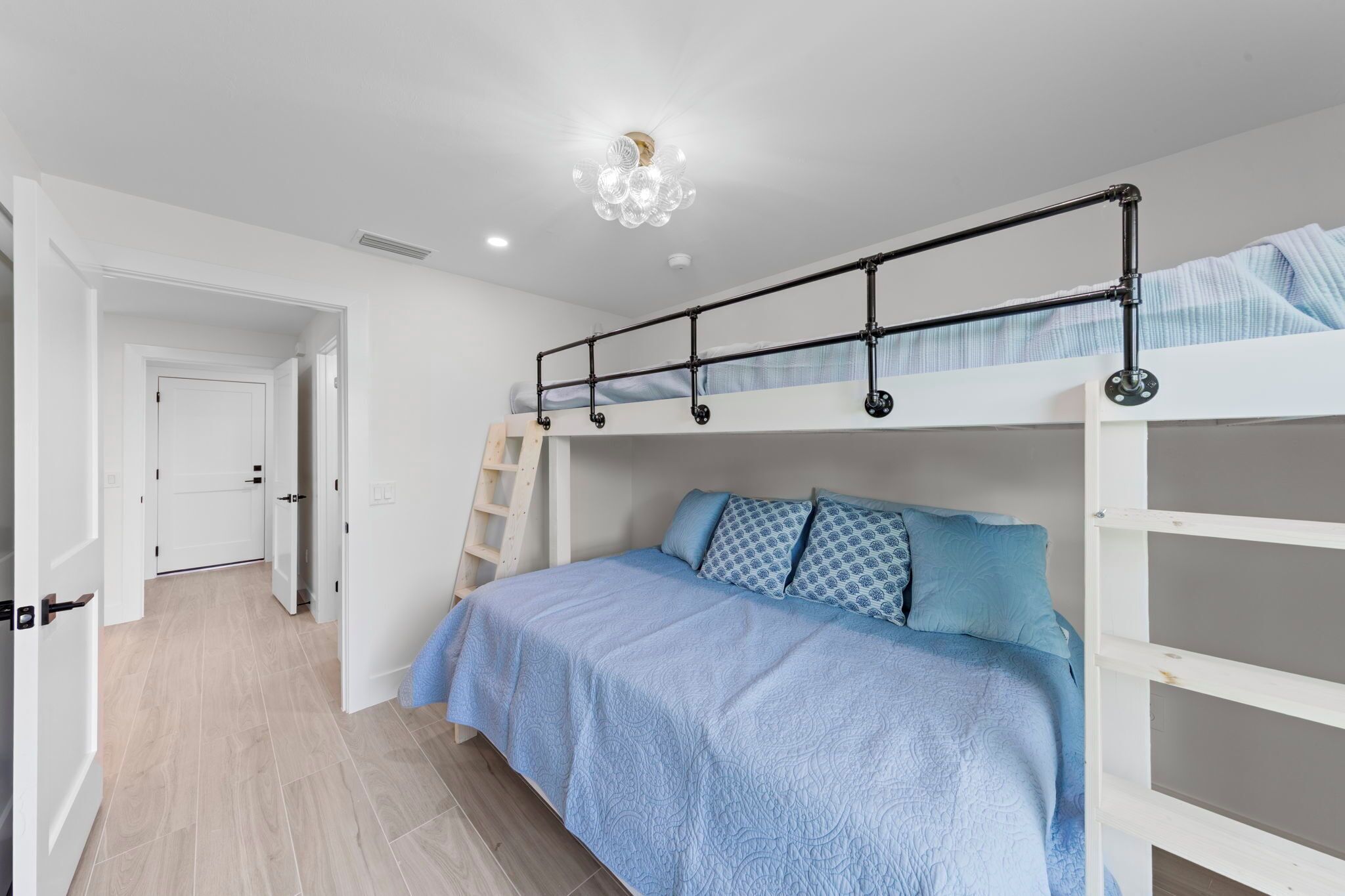 A bedroom with a bunk bed, a ladder, and a chandelier.