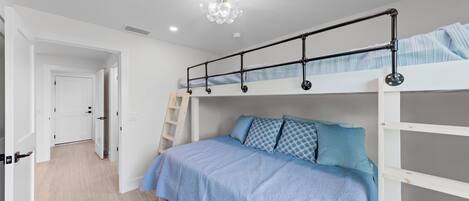 A bedroom with a bunk bed, a ladder, and a chandelier.