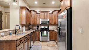A kitchen with wooden cabinets, a stainless steel refrigerator, a double oven, and a microwave. - Resort Condo with Lazy River & Pools (Hurricane)
