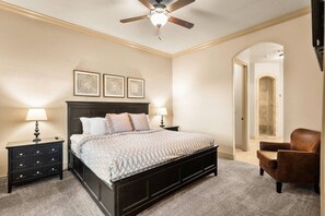 A bedroom with a bed, two bedside tables, a ceiling fan, and a chair. - Resort Condo with Lazy River & Pools (Hurricane)