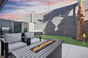 Eine Außenpatio mit Feuerstelle, Sitzgelegenheiten und Grill.