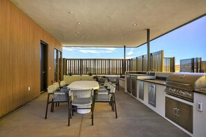 Een terras buiten met een eettafel en stoelen, een barbecue en uitzicht op het landschap.