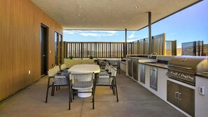Un patio al aire libre con una mesa redonda y sillas, una parrilla y vistas del paisaje.