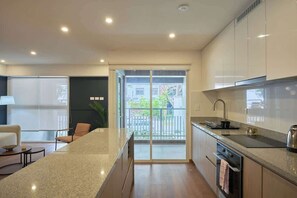 Eine moderne Küche mit einer großen Kochinsel, integriertem Backofen und einer Schiebetür zum Balkon.