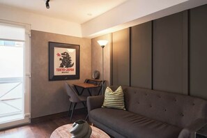 Un salon moderne avec un canapé, un tableau encadré, une lampe et une petite table.