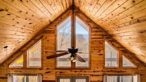 A room with a sloped wooden ceiling, a ceiling fan, and multiple windows. - 5* Family Cabin~View~Hot Tub~FirePit~Pools~Bears (Gatlinburg)