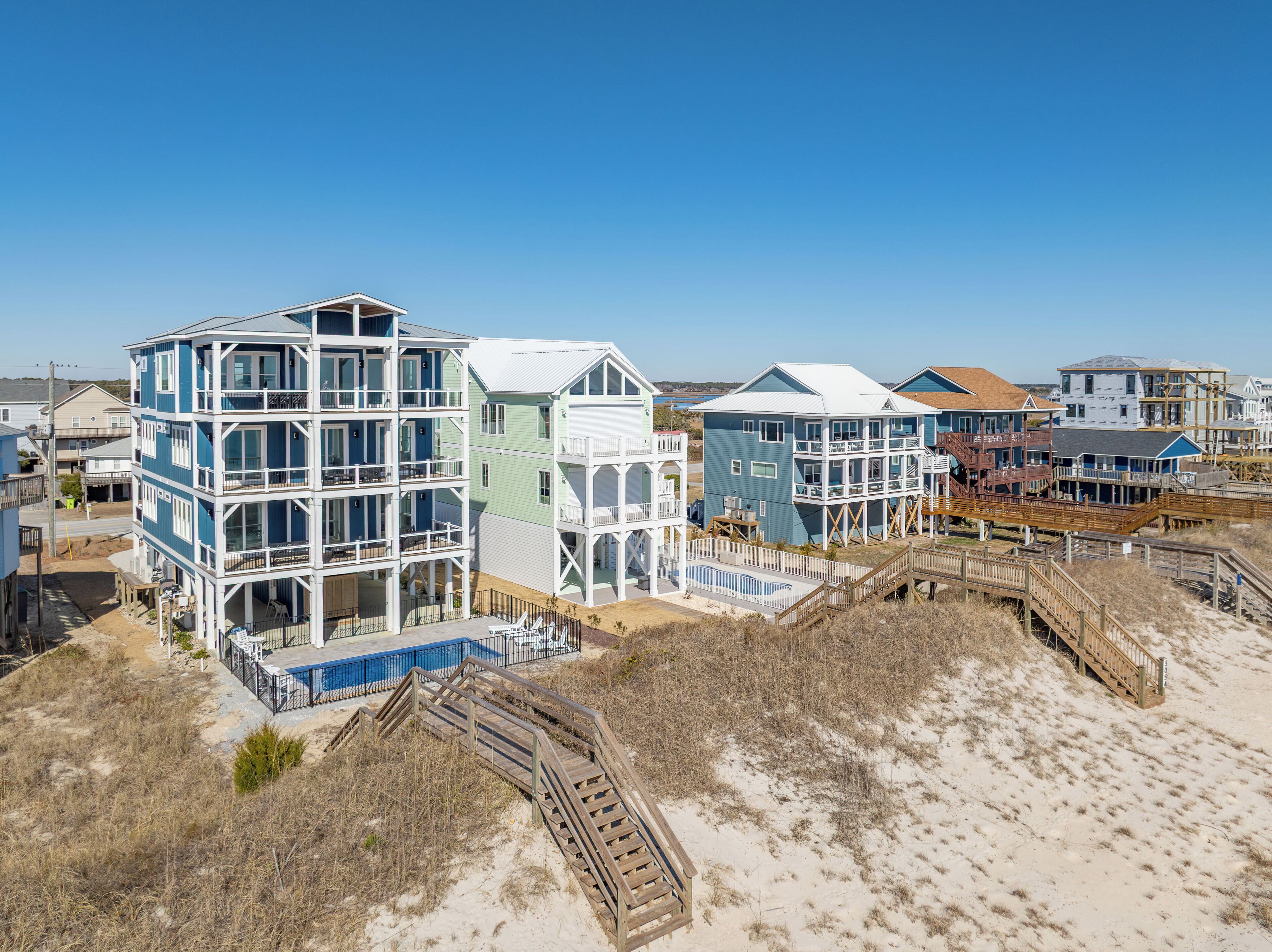 A beachfront property with multi-level buildings, a swimming pool, and wooden walkways.
