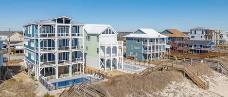 A beachfront property with multi-level buildings, a swimming pool, and wooden walkways.
