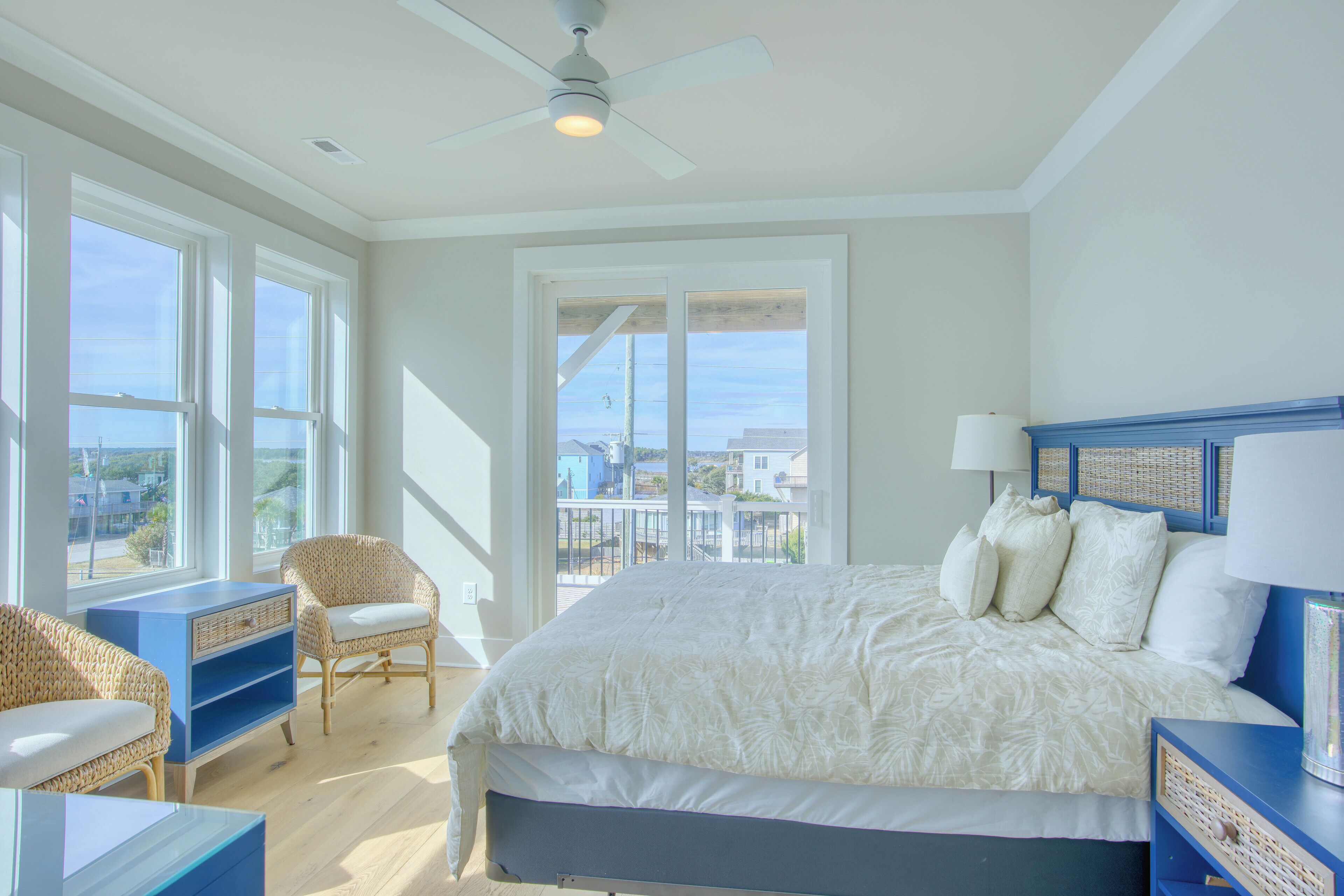Quarto com cama grande, ventilador de teto e vista para o exterior.