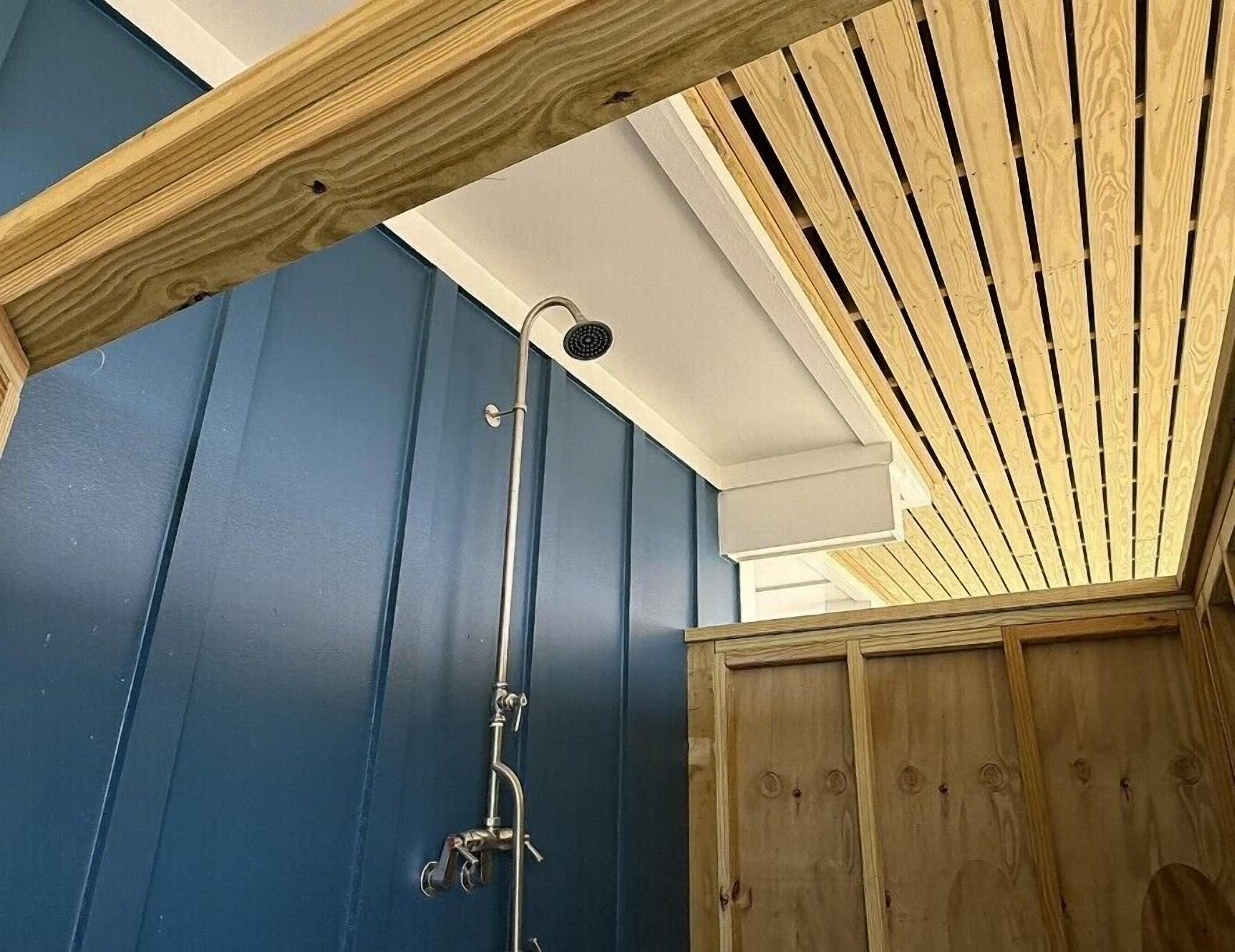 Een douche met een houten plafond en blauwe wanden.
