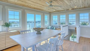 A spacious dining area with a wooden ceiling, large windows, and a view of the landscape. - Atlantis | Ocean Views, Private Saltwater Pool, Elevator, Pets, Beach access (Topsail Beach)