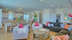 A spacious living area with a dining table, sofas, and a ceiling fan. - Atlantis | Ocean Views, Private Saltwater Pool, Elevator, Pets, Beach access (Topsail Beach)