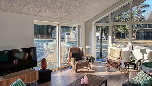 Un salón amplio con televisor grande, asientos cómodos y ventanas grandes que ofrecen vistas al exterior.