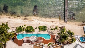 Vue aérienne d’un complexe hôtelier doté d’une piscine, de plusieurs espaces de détente et d’une plage.
