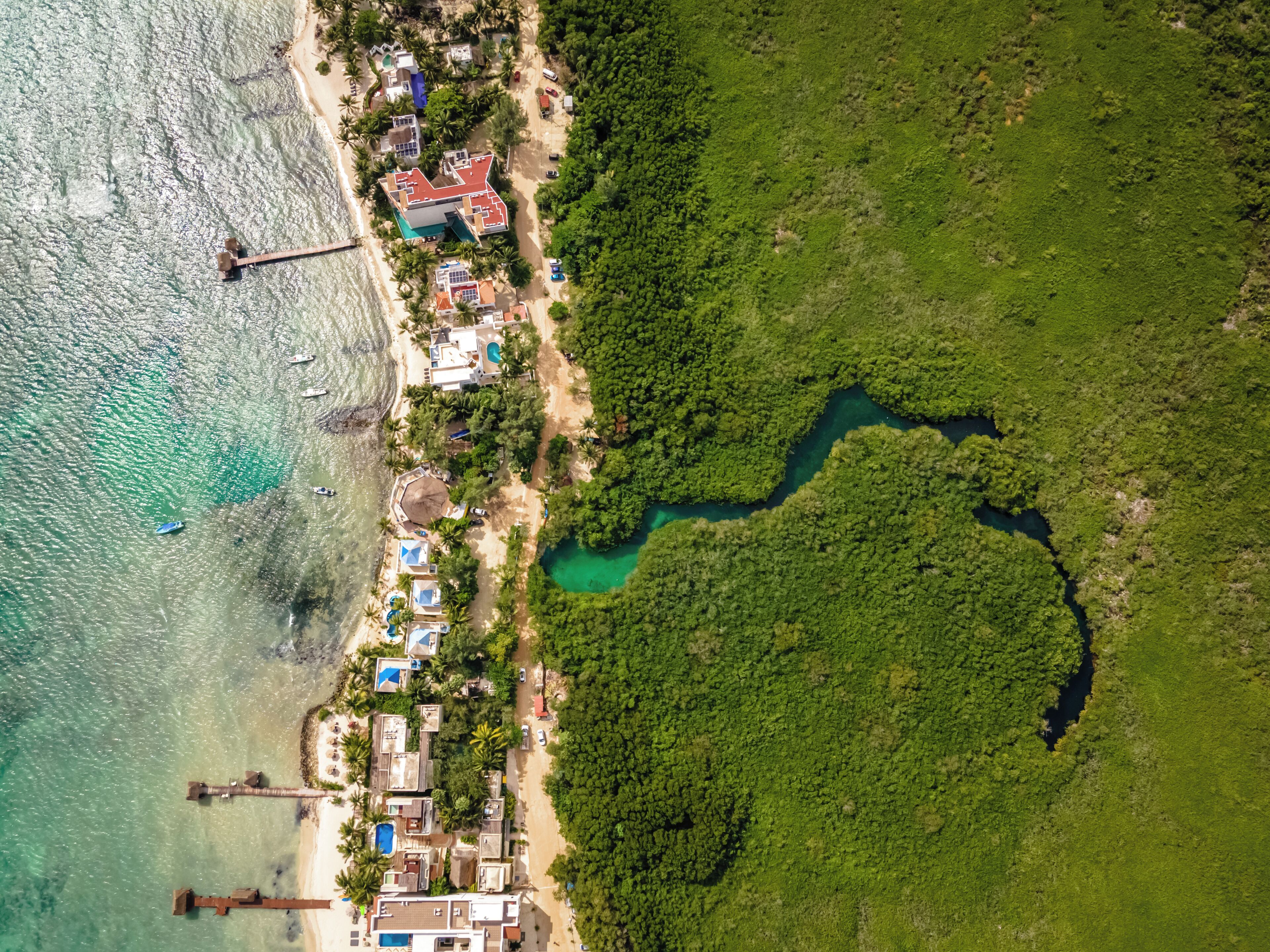 An aerial view of a coastal resort with multiple buildings, a beach, and a river.